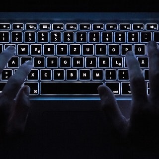 Ein Mann benutzt die beleuchtete Tastatur eines Notebooks