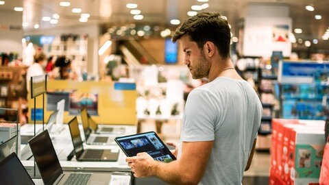 Mann sucht Laptop im Laden aus