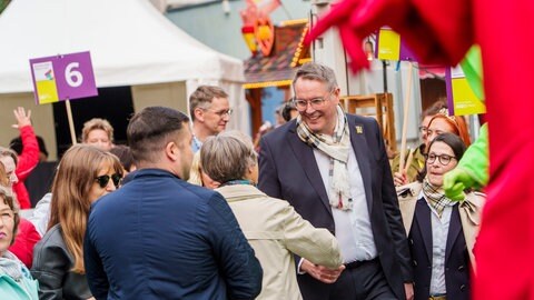 RLP-Tag: Ministerpräsident Schweitzer und seine Ehefrau begrüßen als Teil einer bunten Parade aus Fuss- und Musikgruppen die Zuschauer. 