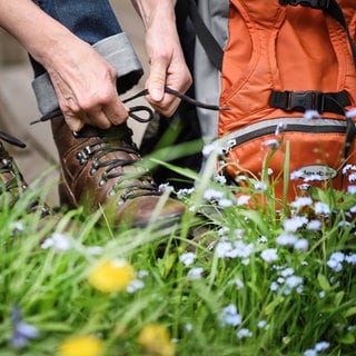 Eine Wandererin schnürt ihre Wanderschuhe. Diese Ausflüge an Ostern lohnen sich jetzt