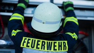 Ein Feuerwehrmann holt Equipment aus einem Einsatzfahrzeug (Symbolbild). In Reutlingen hat ein 12-Jähriger durch Zündelei eine Hecke in Brand gesetzt. 