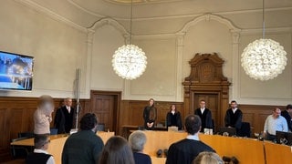 Das Gericht betritt den am ersten Prozesstag den Gerichtssaal. Ein 21-Jähriger ist angeklagt, seine Mutter ermordet zu haben. 