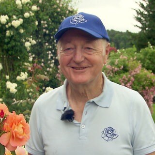 Mann steht in seinem Rosengarten