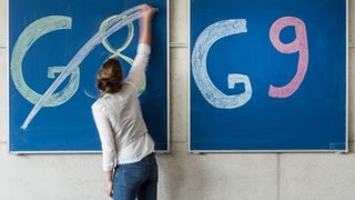 Eine Schülerin streicht auf einer Tafel den Schriftzug "G8" durch. Auf einer Tafel daneben steht in großer Schrift "G9". Die Rückkehr war eine der großen schulpolitischen Reformen in der Amtszeit von Ministerpräsident Kretschmann.