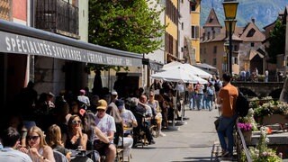Menschen sitzen auf der Terrasse eines Restaurants am Fluss Thiou in der Altstadt. Annecy, Frankreich. Symbolfoto.