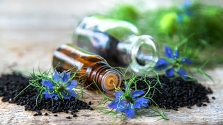 Schwarzkümmelöl in einer Flasche mit Blüte