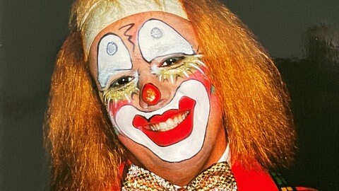 Ein Laufnarr der Narrenzunft Rottenburg, genannt Bogges, mit Glatze, rotem Haar und geschminkem Clownsgesicht.