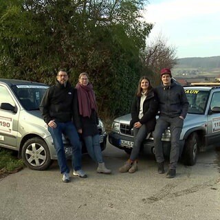 Zwei Paare stehen vor ihren Autos
