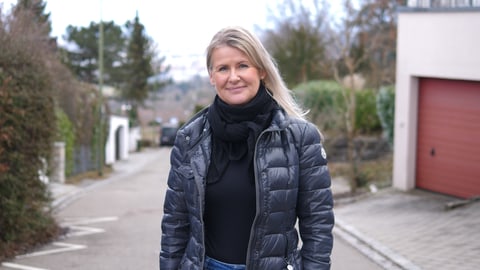 Migräne-Patientin Simone ist eine blonde Frau Anfang 50, sie schaut in die Kamera und steht auf einem Weg.