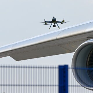 Eine Drohne der Polizei ist über einer Flugzeugtragfläche zu sehen