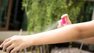 Mückenspray wird auf Arm aufgesprüht