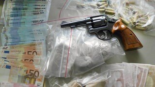 (Symbolbild) Auf einem Tisch liegen Geld, Drogen und eine Waffe.