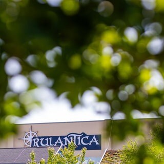 Zwischen Blättern lugt ein Stück einer Gebäudefassade hervor mit der Aufschrift "Rulantica".
