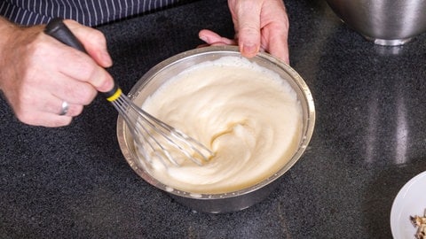 Stollenparfait, das Dessert zum Weihnachtsmenü: Sahne wird in einer Schüssel in die cremige Masse gerührt. 