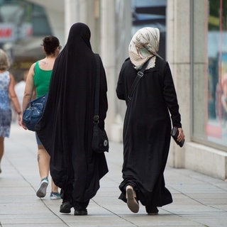zwei muslimische Frauen in langen Gewändern und Kopftuch in Fußgängerzone, Symbol für "Wie hat sich das Leben von Muslimen seit den Terroranschlägen 2001 verändert?"