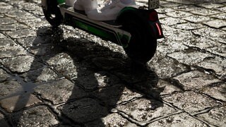 Eine junge Frau in Kaiserslautern ließ sich eine Probefahrt mit einem E-Scooter geben und verschwand dann spurlos mit dem Roller (Eine junge Frau fährt mit einem E-Roller auf einer nassen Strasse).