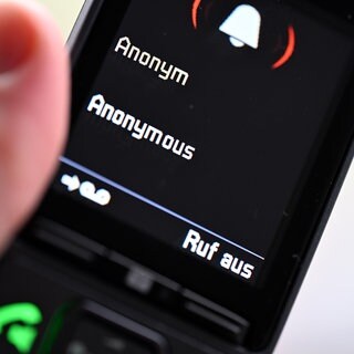 Ein Mann hält ein Festnetz-Telefon, auf dem ein anonymer Anruf eingeht (gestellte Szene). Laut neuer Kriminalstatistik gab es 2025 mehr betrügerische Anrufstraftaten in Baden-Württemberg