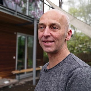 Dirk Adam steht vor seinem Haus in der Nähe von Freiburg. In den Ferien macht er Haustausch.