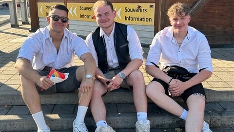Drei Besucher sitzen vor dem Infostand auf dem Stuttgarter Frühlingsfest.