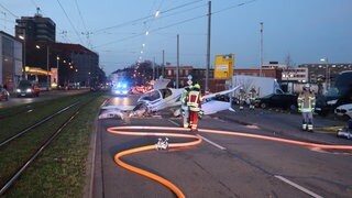 Das Wrack eines Segelflugzeugs liegt mitten auf einer befahrenen Straße. Im Hintergrund die Stadtbahn. Ein Leichtflugzeug musste im Mannheimer Stadtgebiet notlanden. Laut Polizeisprecherin kam es mitten auf der vielbefahrenen Neckarauer Straße zum Stehen.