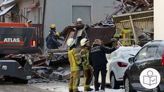In Albstadt ist ein Haus eingestürzt. Es gab eine Explosion. Ein Polizist und Feuerwehrleute stehen vor den Trümmern. Rechts das SWR Logo für Leichte Sprache.