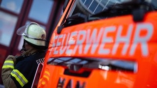 Ein Feuerwehrmann steht neben einem Einsatzwagen (Symbolbild). Bei einer Betriebspanne in Ludwigshafen wurden größere Mengen Mehlstaub und Mineralien freigesetzt.