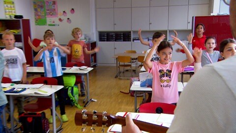 Grundschüler singen ein Lied im Klassenzimmer. Die Schule in Bodelshausen hat ein Konzept gegen Elterntaxis.