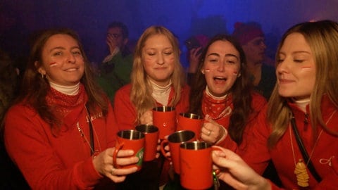 Eine Garde-Gruppe stößt auf einer Party mit roten Alubechern an.