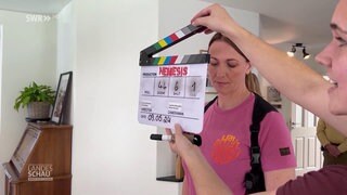 Eine Frau hält eine Filmklappe vor eine Schauspielerin