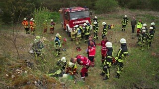 Viele Rettungskräfte stehen am Einstieg zu einer unterirdischen Höhle. Auch die Feuerwehr ist vor Ort.