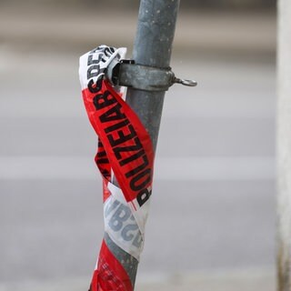 Polizeiabsperrband an einem Straßenschild.