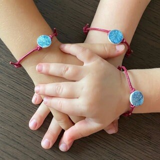 Das sind die Hände von drei "großen" Schwestern. Sie tragen Armbänder mit den Fingerabdrücken ihres kleinen Bruders. Er wurde nur 15 Tage alt. 