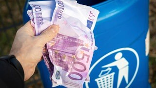 Eine Person hält mehrere 500 Euro-Scheine in der Hand und ist im Begriff diese in einen Mülleimer zu werfen. Der Bund der Steuerzahler hat sein "Schwarzbuch" mit Fällen veröffentlicht, in denen seiner Ansicht nach Geld verschwendet wird.