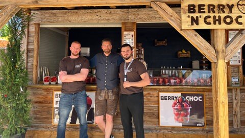 Drei Männer stehen vor einem Essensstand auf dem Stuttgarter Frühlingsfest.
