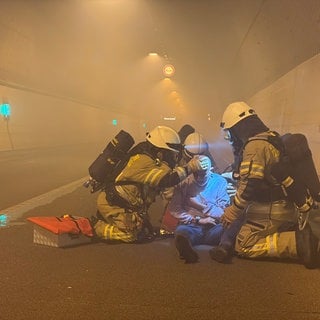 Einsatzkräfte im Tunnel versorgen in dichtem Rauch einen Verletzten.