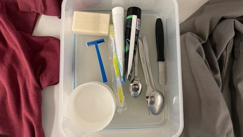 Ein Plastikbehälter mit einem Rasierer, Löffel, Tuben, einer Seife und mehr. Dieses Set bekommen Gefangene, wenn sie in die JVA Frankenthal eingewiesen werden.