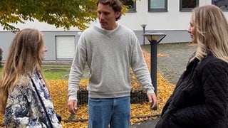 Zwei Frauen und ein mann stehen auf einem Platz draußen