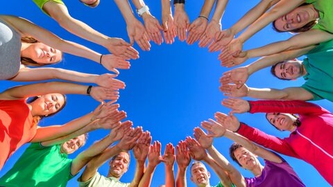Viele Menschen stehen im Kreis und bilden mit ihren Händen einen inneren Kreis