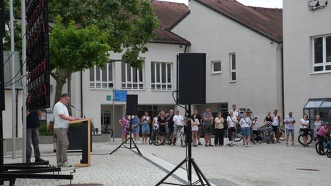 Bürgermeister Stefan Wörner (parteilos) steht auf dem Marktplatz und verkündet einigen Zuschauern das Ergebnis des Bürgerentscheiids.