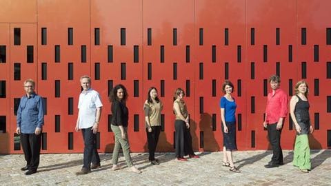 Gruppenbild Ensemble Experimental vor rotem Haus mit vielen kleinen Fenstern