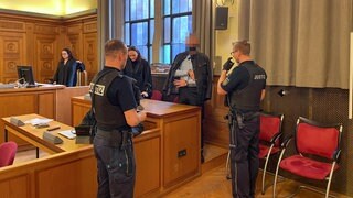 Ein Angeklagter in Handschellen und Justizmitarbeiter in einem Saal am Landgericht Tübingen. Das hat einen 26-Jährigen zu einer Gefängnisstrafe verurteilt