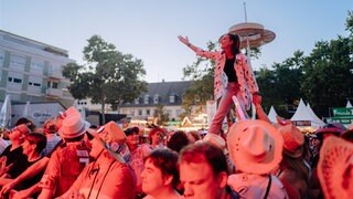 Menschen feiern im Abendlicht vor einer Bühne auf dem Strohhutfest in Frankenthal