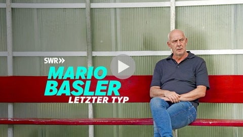Das Keyvisual zeigt Mario Basler auf einer roten Bank am Spielfeldrand sitzend.