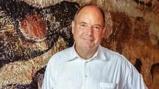 Prof. Nicholas Conard, Archäologe an der Uni Tübingen, steht in einer Höhle vor urgeschichtlichen Malereien. 
