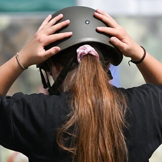 Archiv: Eine junge Frau setzt sich auf dem Gelände der Sonderschau der Bundeswehr einen Helm auf.