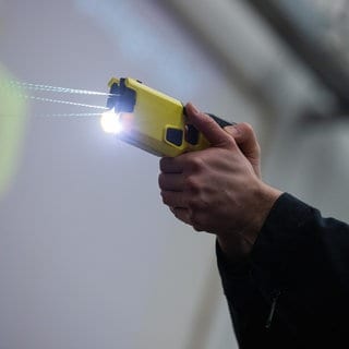 Ein Polizeibeamter demonstriert einen Schuss mit einem Taser.
