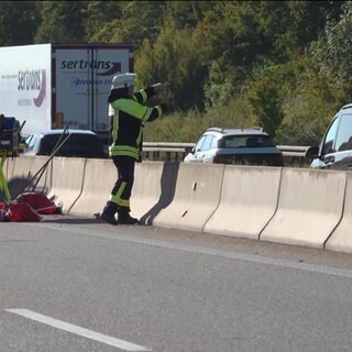 Ein Feuerwehrmann filmt und zeigt in Richtung eines Gaffers auf der Autobahn