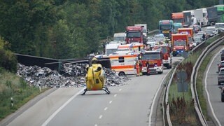 Auf der A61 liegt ein Lkw, der Metallschrott geladen hatte. Davor steht ein Rettungshubschrauber.