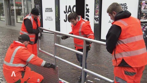 Arbeiter befestigen eine Metallabsperrung auf der Straße