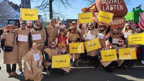 Motivwagen mit Esel und Fußgruppe mit Städtevertretern im Jutesack auf Düsseldorfer Rosenmontagsumzug 